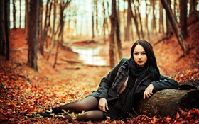 Niña de pelo negro en el bosque, otoño, las hojas amarillas